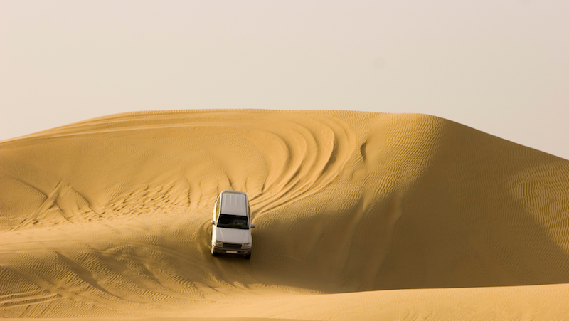 Landcruiser driving off-road down sand dune