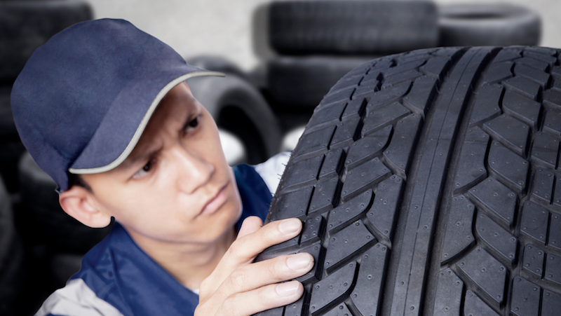 Tyre technician inspecting used tyre for fitment